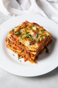 a white plate topped with lasagna on top of a table next to a fork