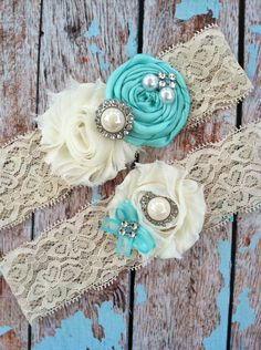 two garters with flowers and pearls are on a wooden surface, one is blue