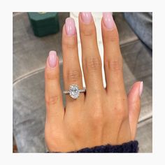 a woman's hand with a diamond ring on her left hand and pink manicured nails