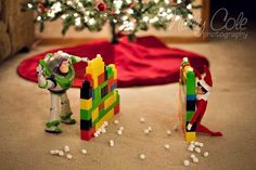 two toy figurines are next to a christmas tree