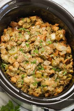 a crock pot filled with stuffing sitting on top of a counter next to parsley