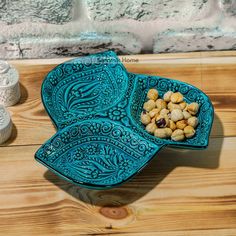 a blue bowl filled with nuts sitting on top of a wooden table next to an empty bottle