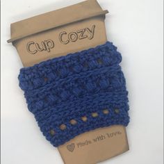 a blue crocheted cup cozy on top of a cardboard box with the words cup cozy written across it