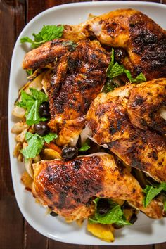 a white plate topped with chicken and veggies on top of a wooden table