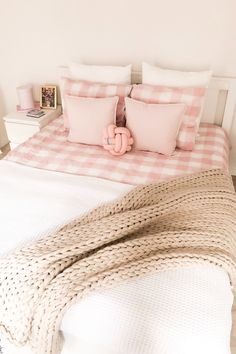 a bed with pink pillows and blankets on it