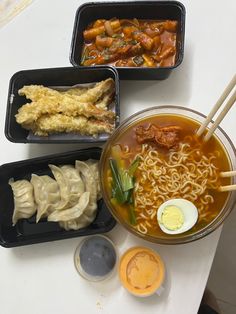 four trays of ramen with chopsticks and an egg on the side