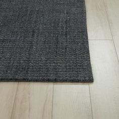 a close up of a rug on the floor with wood floors and white walls in the background