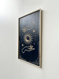 a painting hanging on the side of a white wall next to a black and gold frame