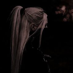 a woman with long blonde hair standing in the dark