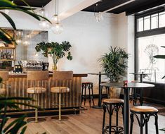 the interior of a restaurant with tables, chairs and potted plants on the wall