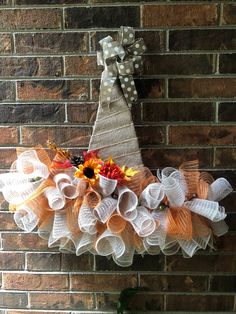 an orange and white mesh wreath hanging on a brick wall