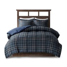 a bed with blue plaid comforter and pillows