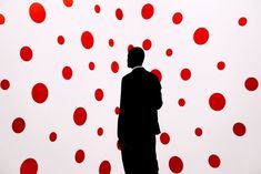 a man standing in front of a red and white wall with circles drawn on it