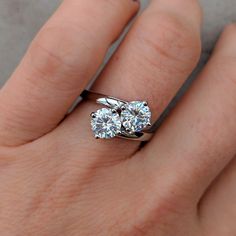 a woman's hand with a diamond ring on top of her finger and an engagement band