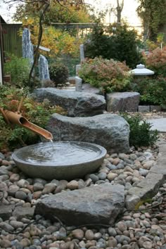 an outdoor fountain surrounded by rocks and trees