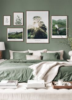 a bedroom with green walls and pictures on the wall above the bed in front of it