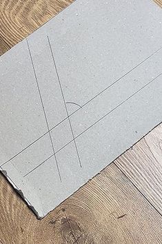 a piece of paper laying on top of a wooden floor next to scissors and tape