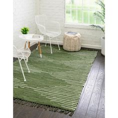 a green rug with white chairs and a table