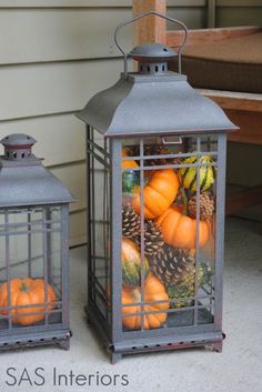 a lantern filled with pumpkins and pine cones