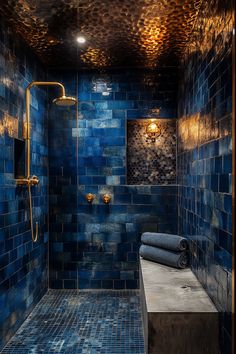 a blue tiled bathroom with gold fixtures and lights on the ceiling, along with a large walk - in shower