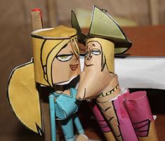 two paper dolls sitting next to each other on a table