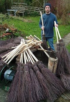 a man standing next to a pile of brooms