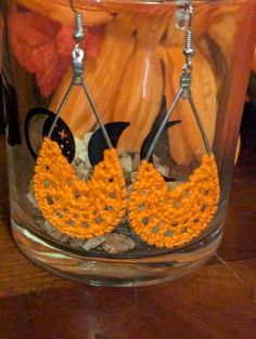 orange and white crocheted earrings are displayed in a jar