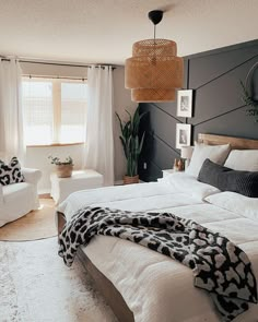 a large bed sitting in a bedroom next to a white chair and window with curtains