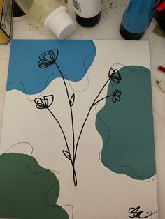 a painting with blue and green flowers in the center on a white surface next to paint supplies