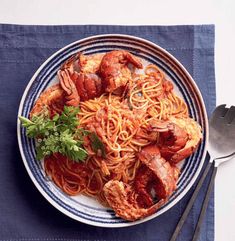 a plate of pasta with lobsters and parsley on the side next to a fork