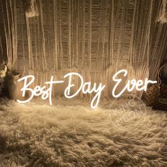 the words best day ever are lit up in front of a bed with white fur