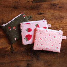 three small zippered pouches sitting on top of a wooden table