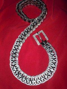 a large silver chain with a buckle on it's end is laying on a red cloth