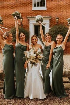 the bride and her bridesmaids are holding their bouquets up in the air