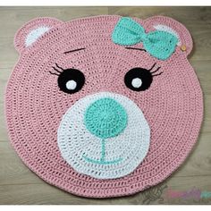 a crocheted pink bear rug with a green bow on it's head