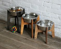 three metal bowls sitting on wooden stands next to a white brick wall and colorful toy