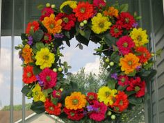 a wreath is hanging on the side of a house in front of a window with flowers