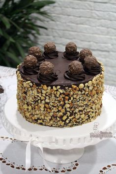 a cake with chocolate frosting and nuts on top sitting on a white platter