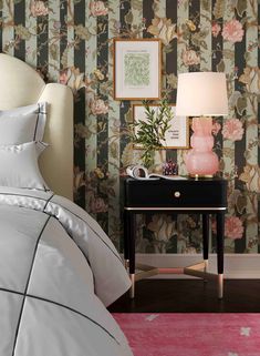 a bedroom with floral wallpaper and a nightstand in the corner next to a bed