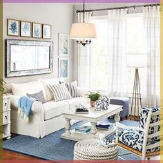 a living room with white furniture and blue rugs in front of a window that has pictures on the wall