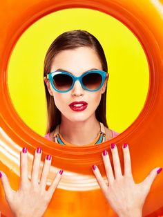 a woman wearing sunglasses and holding an orange frisbee in front of her face