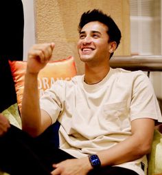 a young man sitting on top of a couch holding a remote control in his hand