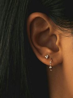 a woman's ear is shown with two small white stones on the end of it