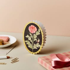 a card with a pink flower on it sitting next to some other cards and scissors