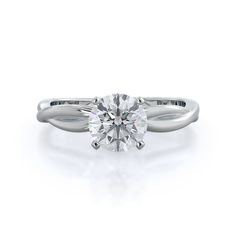 a white gold engagement ring with a round cut diamond in the center, on a plain surface