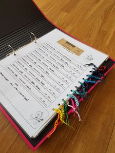 an open binder on the floor with music notes attached to each ring and string