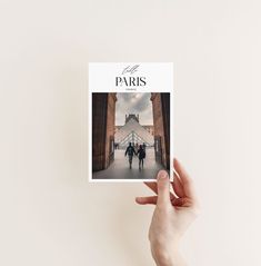 a hand holding up a paris travel guide