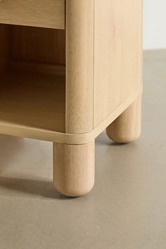 a close up of a wooden shelf on the floor with an open drawer underneath it