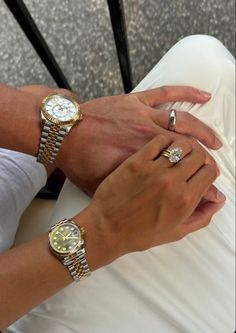 two people wearing gold and silver watches on their hands, one holding the other's hand