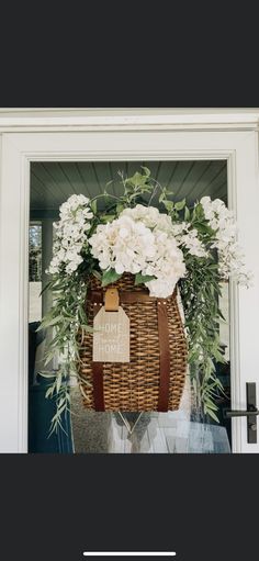 a basket filled with white flowers sitting on top of a door